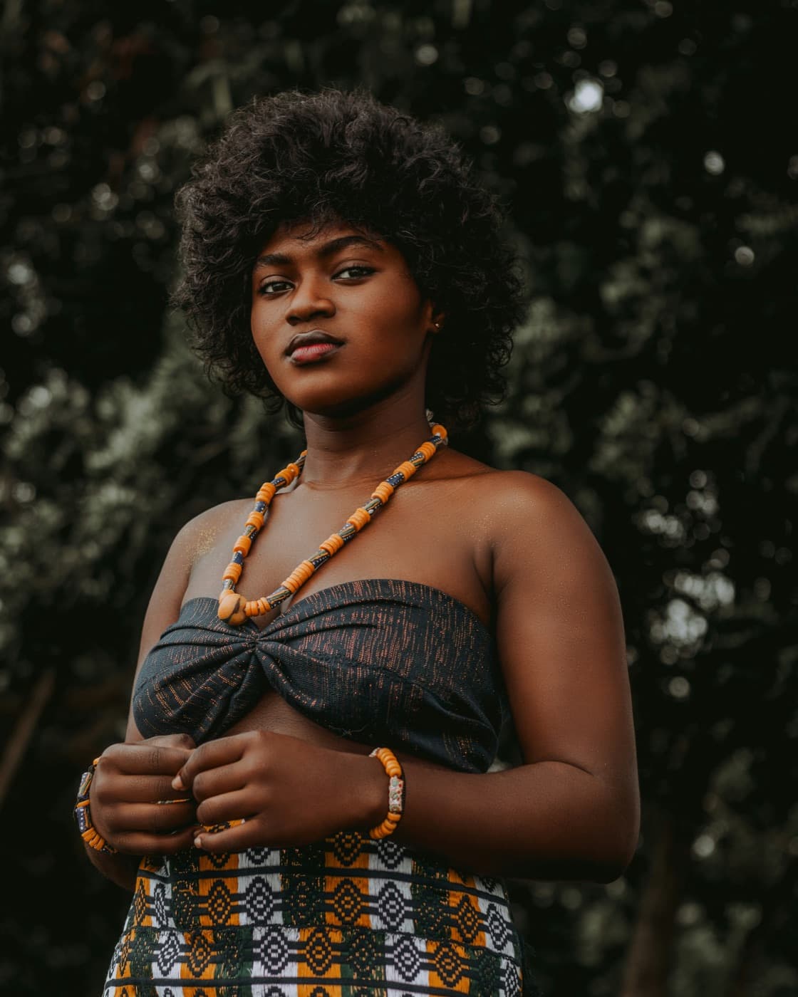 A young woman wearing a handmade beaded necklace and bracelets with patterned traditional attire in Tema, Greater Accra